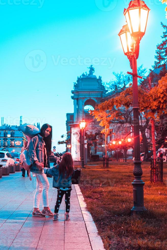 peuter- meisje en moeder in de avond stad foto