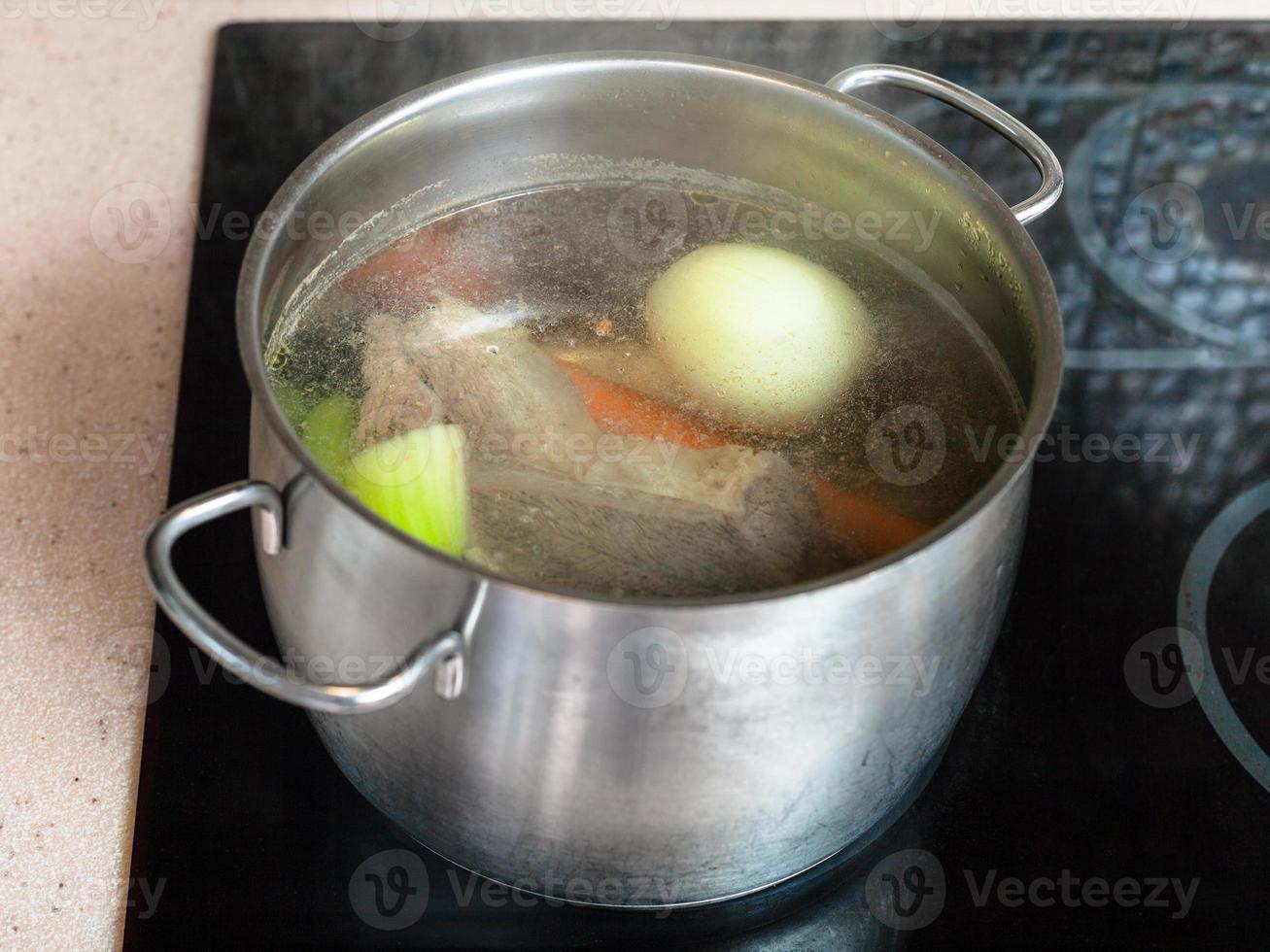 sudderen vlees bouillon in soeppan Aan keramisch kookplaat foto