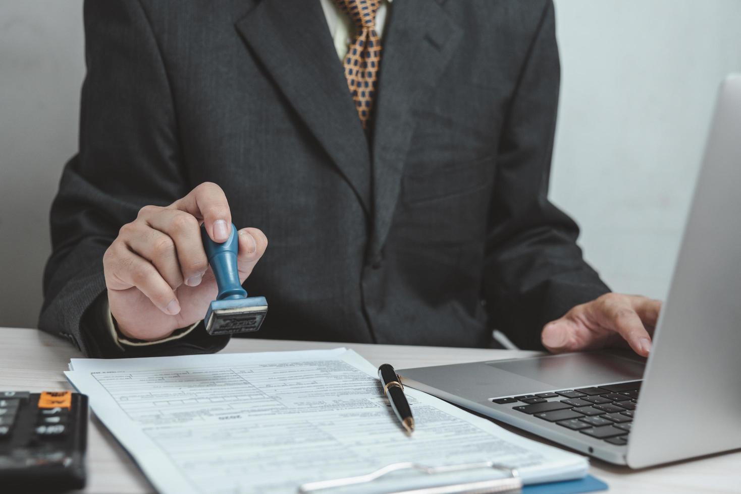 Mens stempelen goedkeuring van werk financiën bank of investering afzet documenten Aan bureau. foto