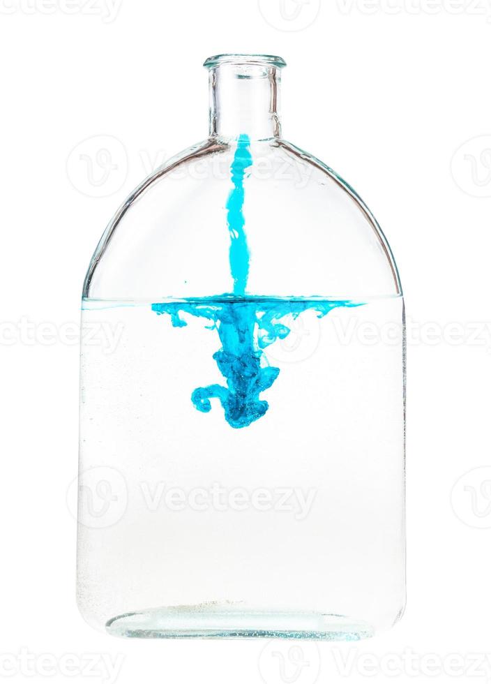 druppelen van blauw inkt stromen in water in glas fles foto