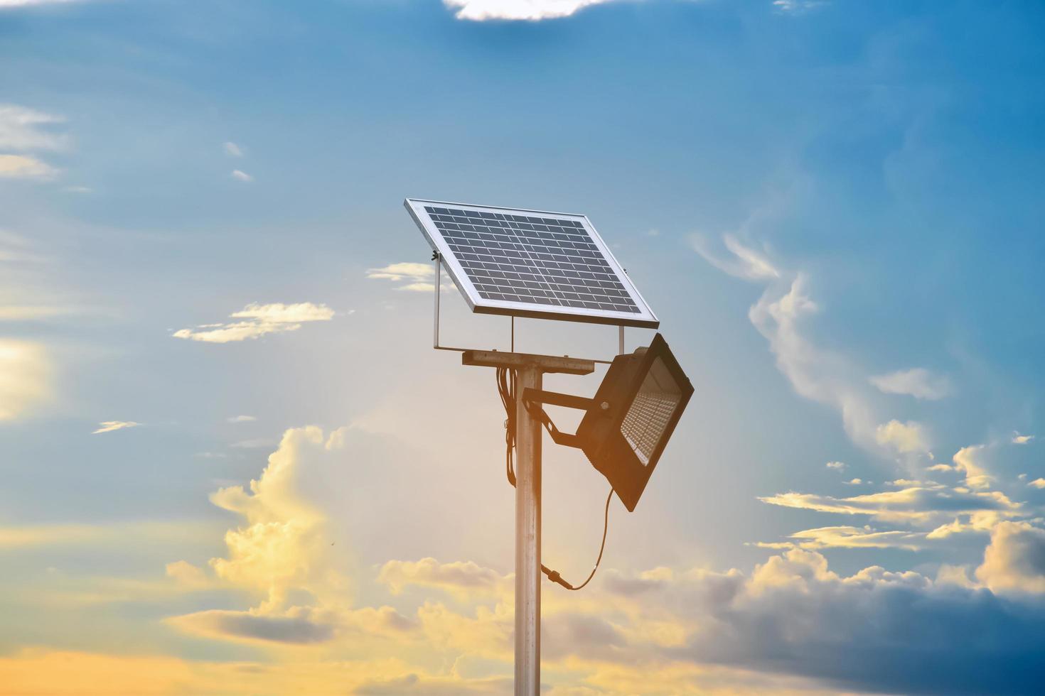 mini zonne- of fotovoltaïsche cel paneel geïnstalleerd Aan metaal pool met schijnwerper LED, wazig bewolkt en blauwe lucht achtergrond, concept voor gebruik makend van natuurlijk energie van de zon in dagelijks leven van menselijk. foto