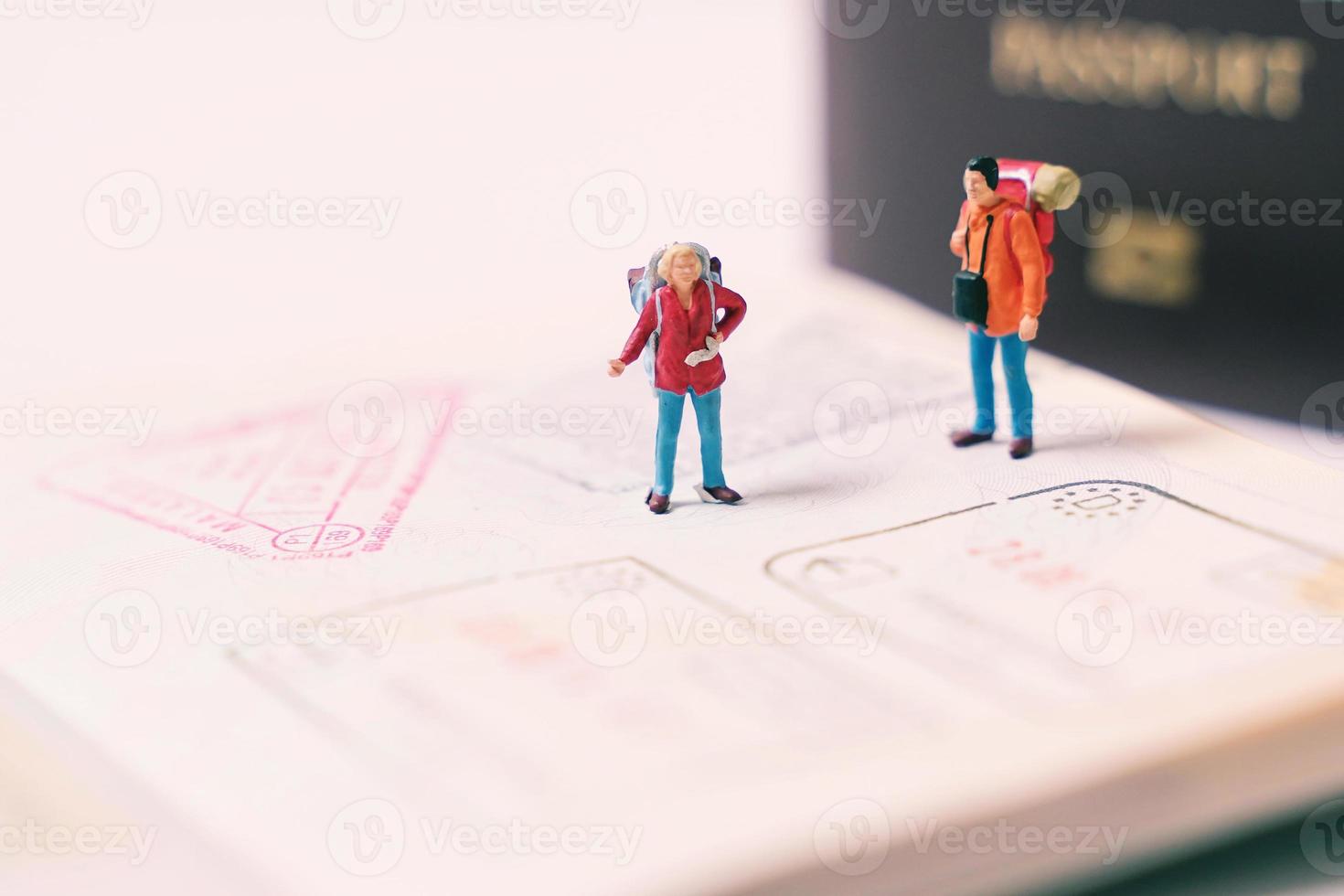 miniatuur mensen figuren met rugzak wandelen en staand Aan paspoort bladzijde met immigratie postzegels, reizen en vakantie concept foto