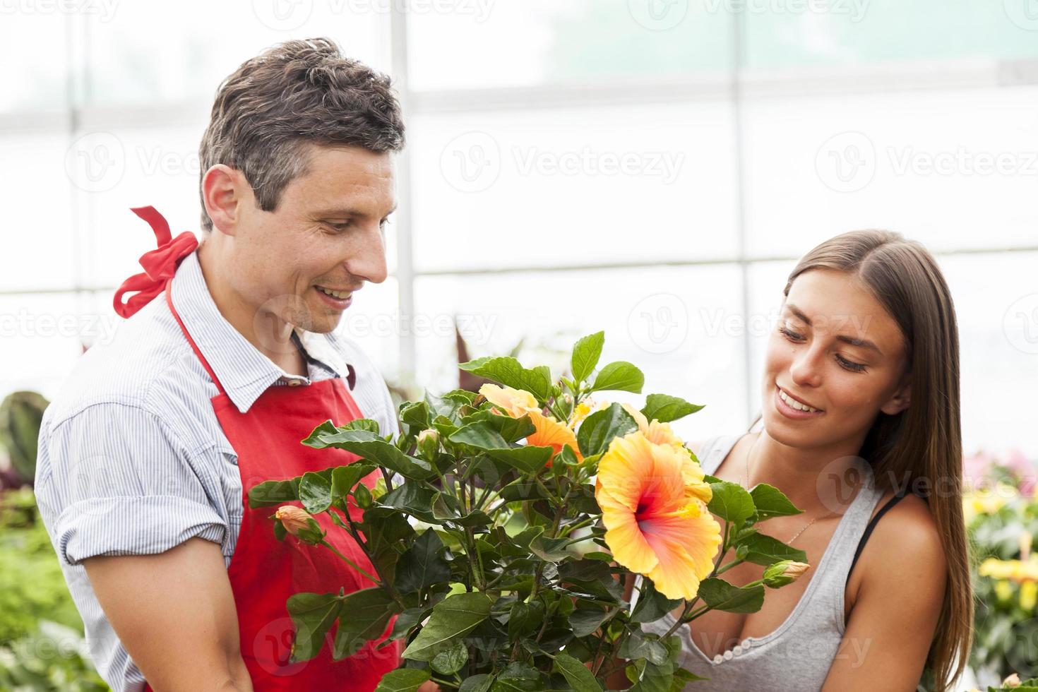 lachende verkoper verkoopt een plant aan een mooie klant foto