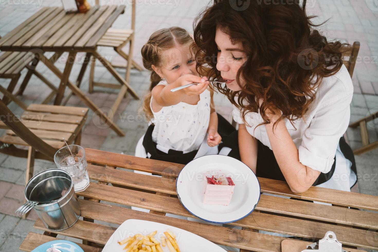 jong mam aan het eten taart met glimlachen kind Aan de straat foto