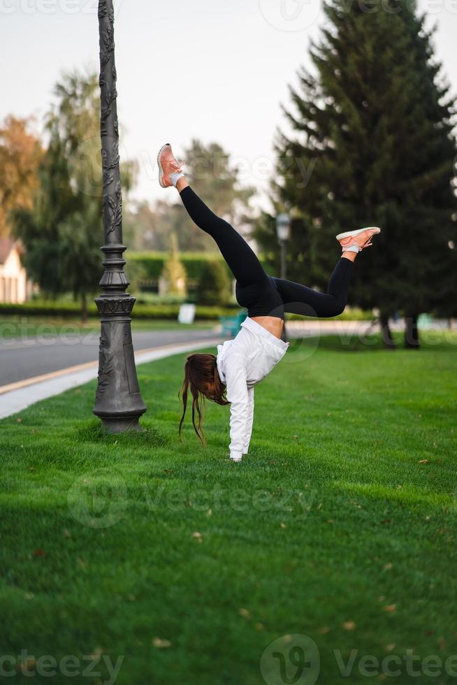 aantrekkelijk mager vrouw aan het doen een achteroverbuigen terwijl tonen een salto. foto