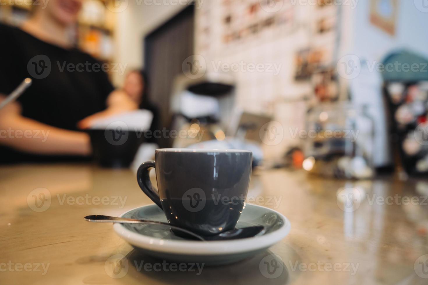 kop van zwart koffie, lepel, houten tafel, Bij een cafe foto