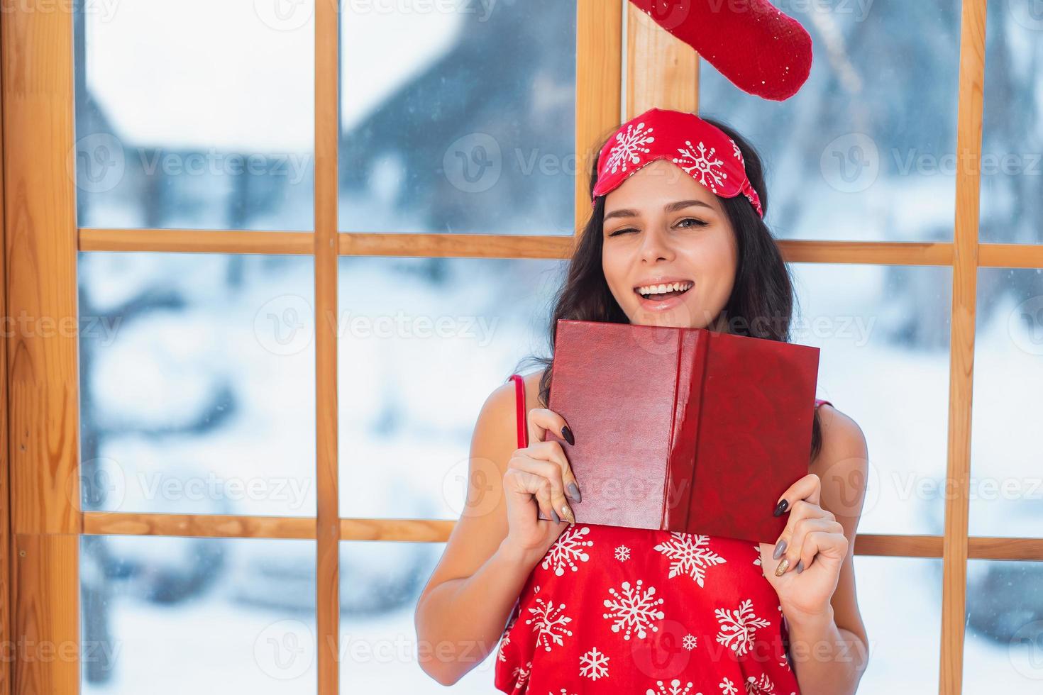 mooi jong brunette vrouw vervelend rood pyjama zittend huis door de venster foto