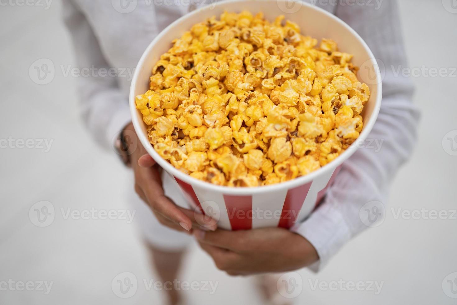 detailopname foto van een jong zoet meisje, wie is Holding een buis van popcorn in haar handen.