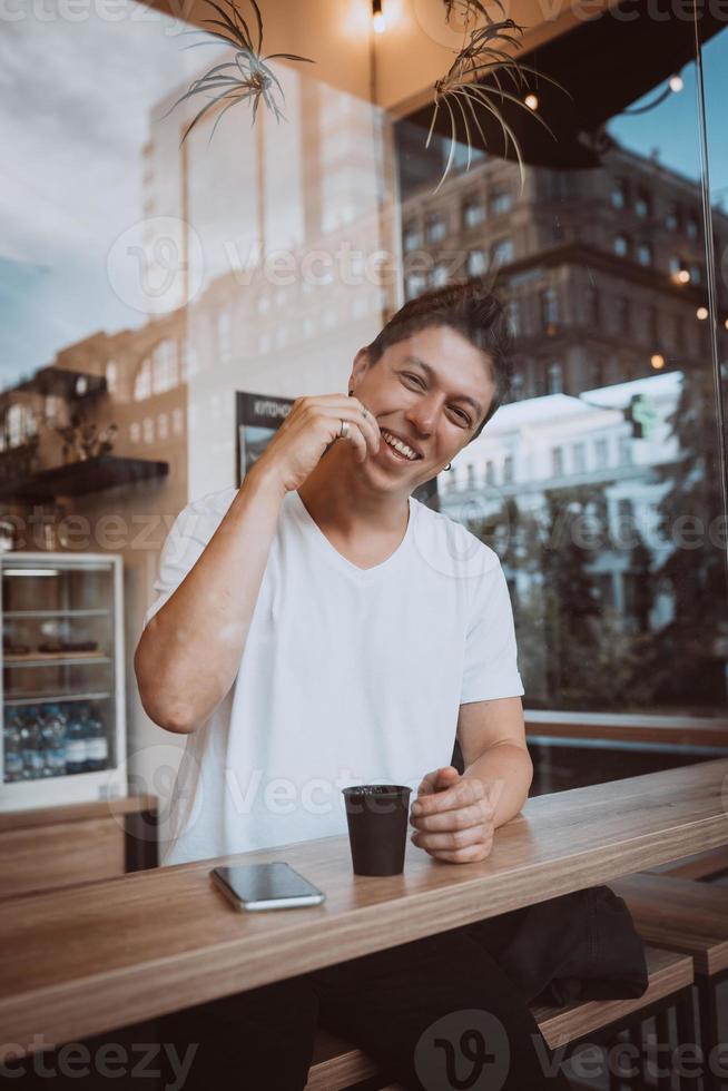 jong, knap Mens is drinken zijn ochtend- koffie in een cafe. foto