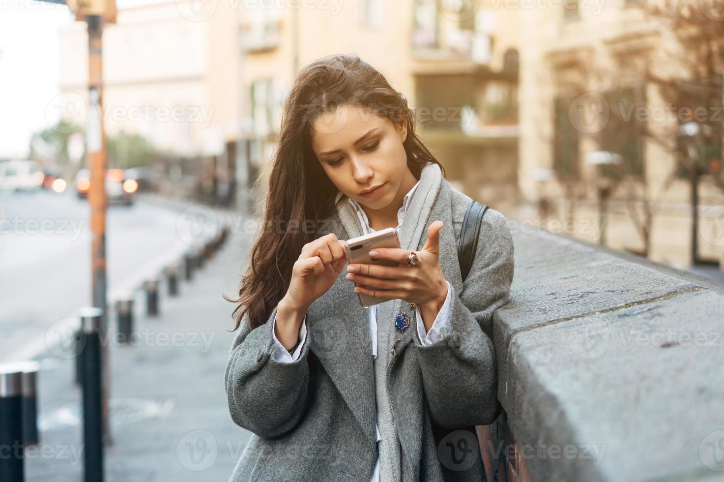 vrouw gebruik makend van haar mobiel telefoon in de straat. foto