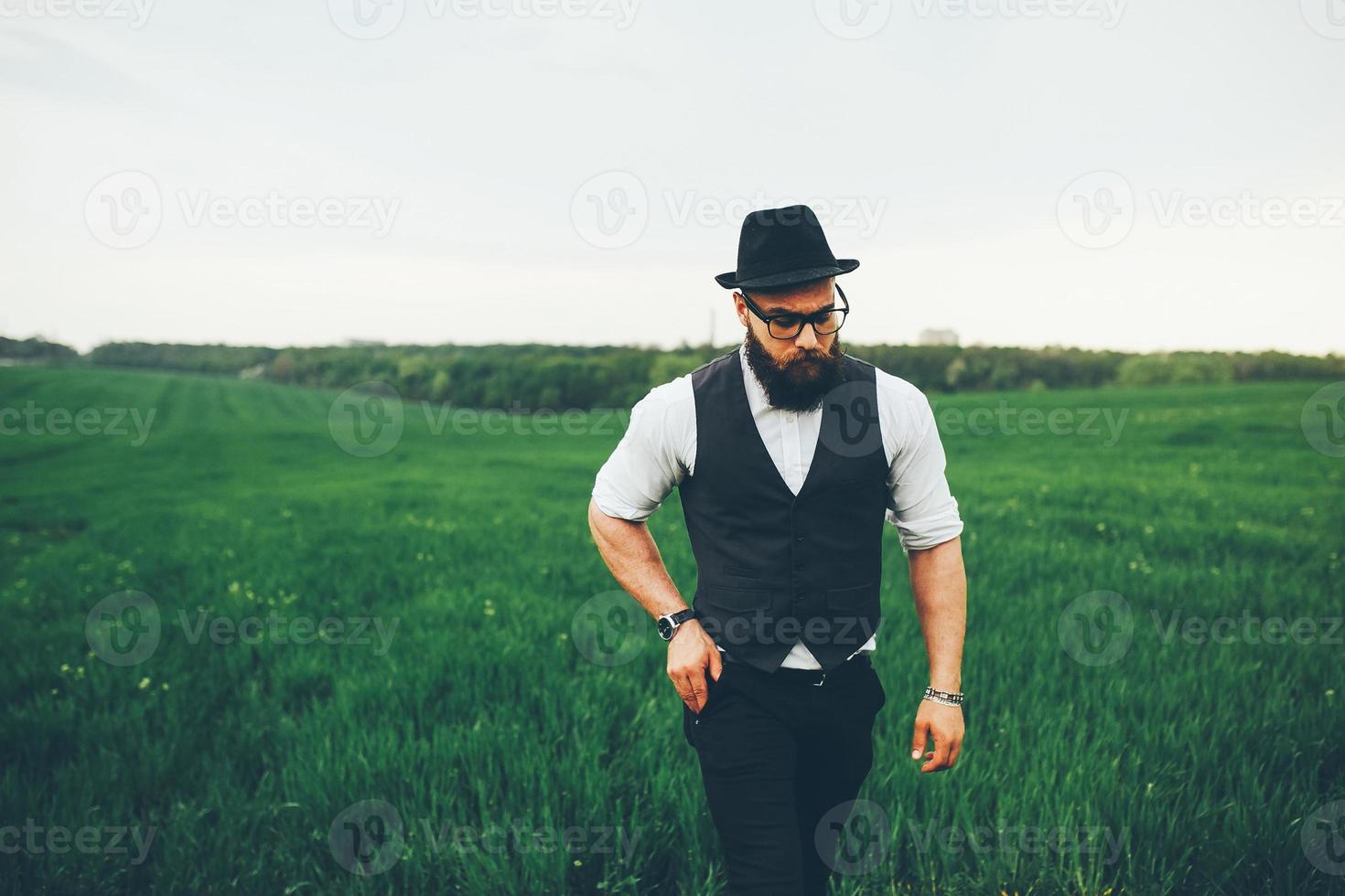 man met een baard en zonnebril lopen op het veld foto
