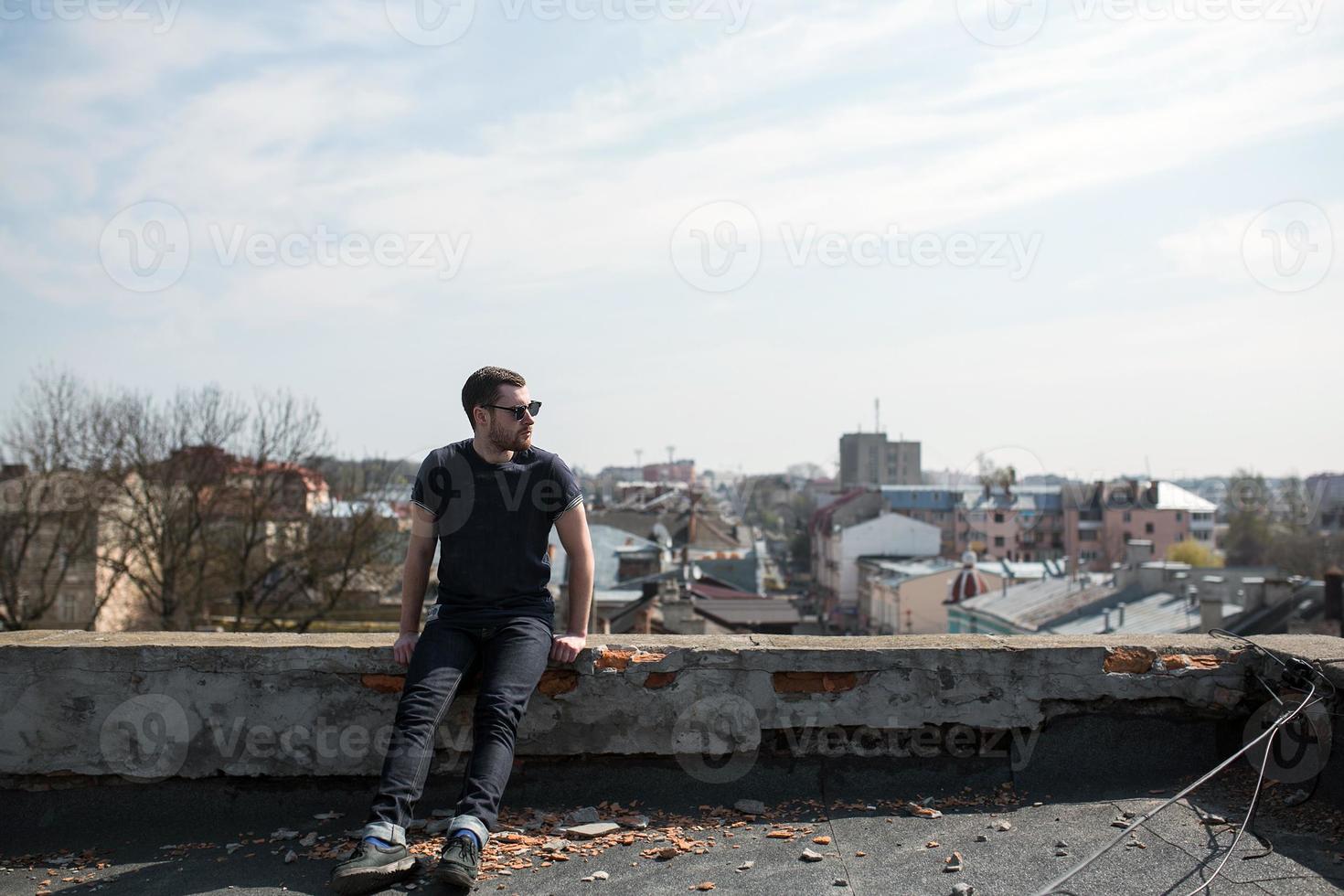 de man in de authentieke zelfkant van laarzen en jeans op het dak van het gebouw in de oude stad foto