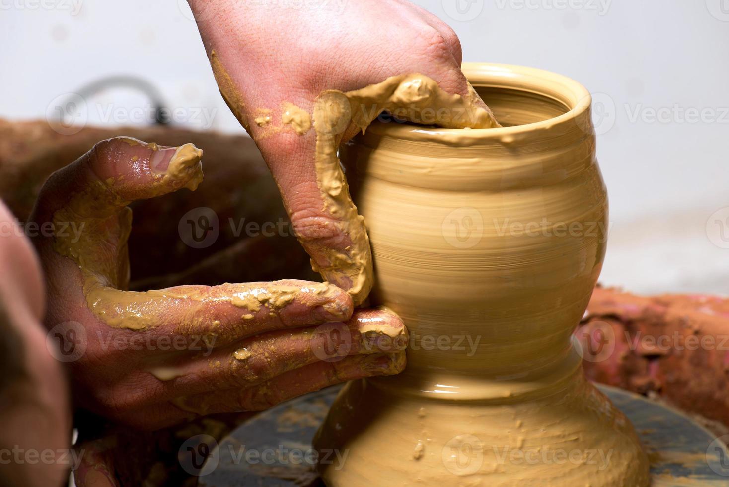 handen van een pottenbakker, waardoor een aarden pot ontstaat foto