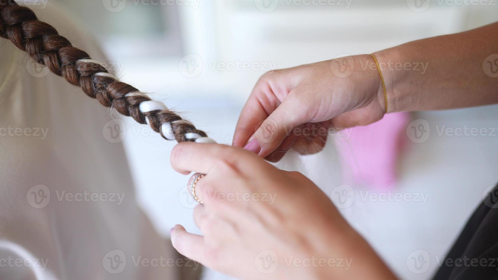 werkwijze van vlechten. meester weeft vlechtjes Aan hoofd in een schoonheid salon, dichtbij omhoog foto