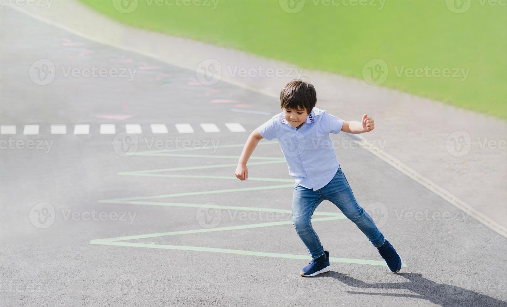 portret van jong jongen rennen of jumping Aan driehoeken lijn Bij asfalt weg, actief kind spelen in de openbaar park Aan zonnig dag voorjaar of zomer, kind Speel en leren buitenshuis werkzaamheid concept. foto