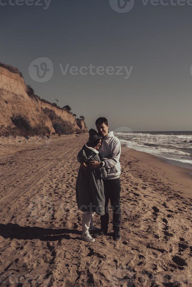 Mens en vrouw in elk die van anderen armen Aan de kust foto