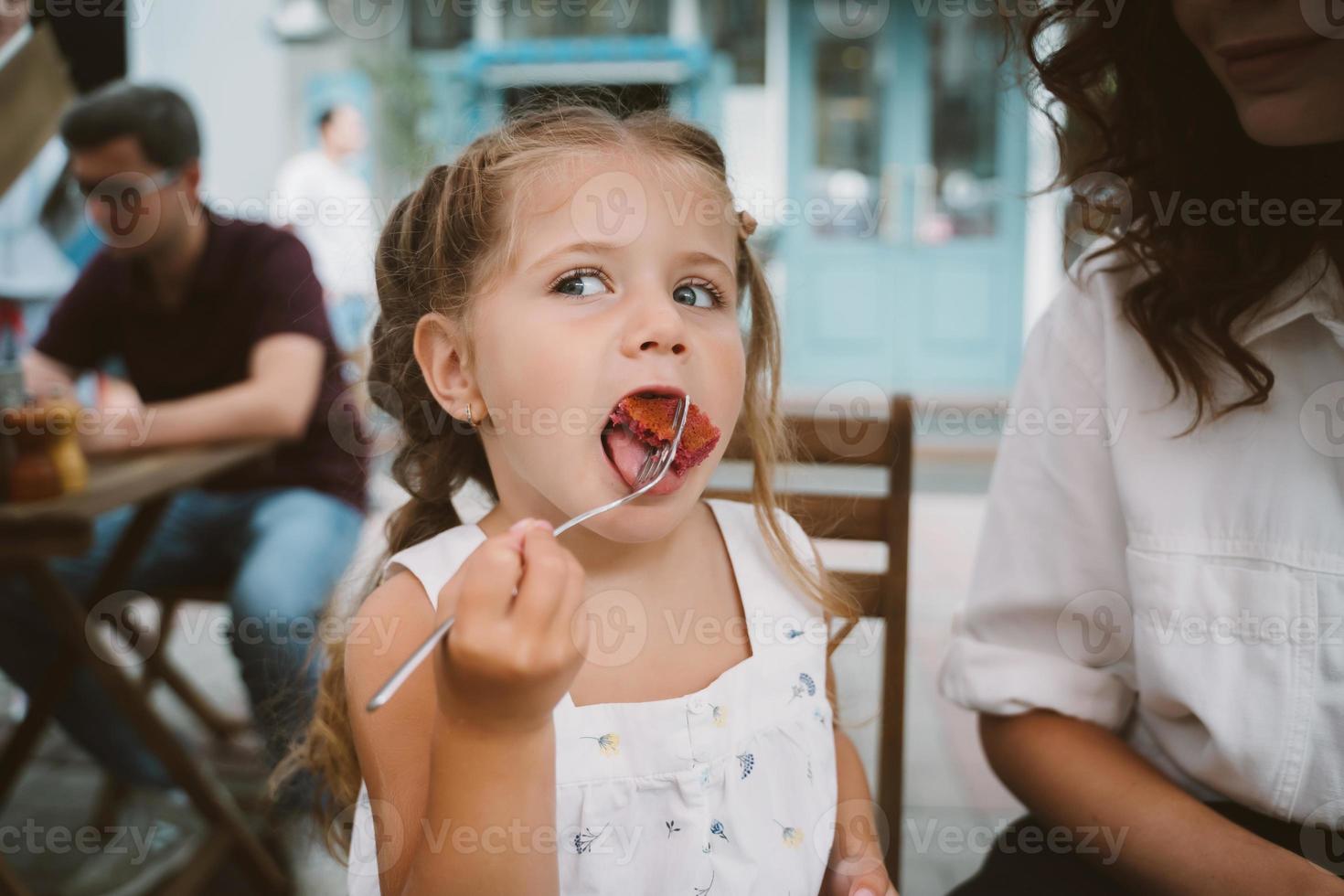 jong mam aan het eten taart met glimlachen kind Aan de straat foto