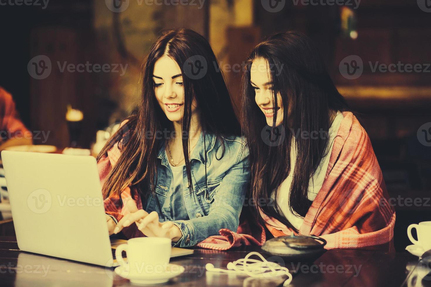 twee meisjes kijken naar iets in de laptop foto