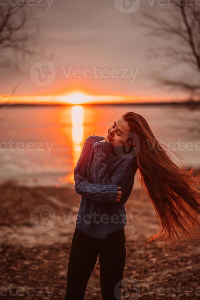 vrouw genieten van tijd ontspannende door de mooi meer Bij zonsopkomst. foto