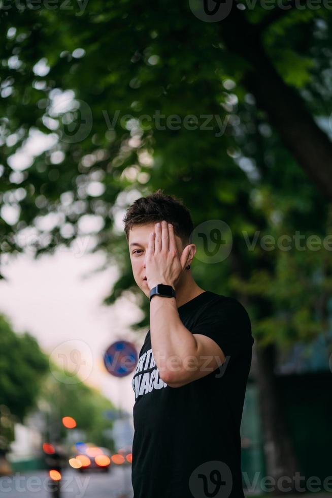 jong volwassen Mens in een zwart t-shirt en jeans wandelingen Aan een stad straat foto