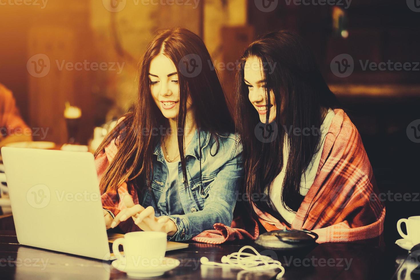 twee meisjes kijken naar iets in de laptop foto