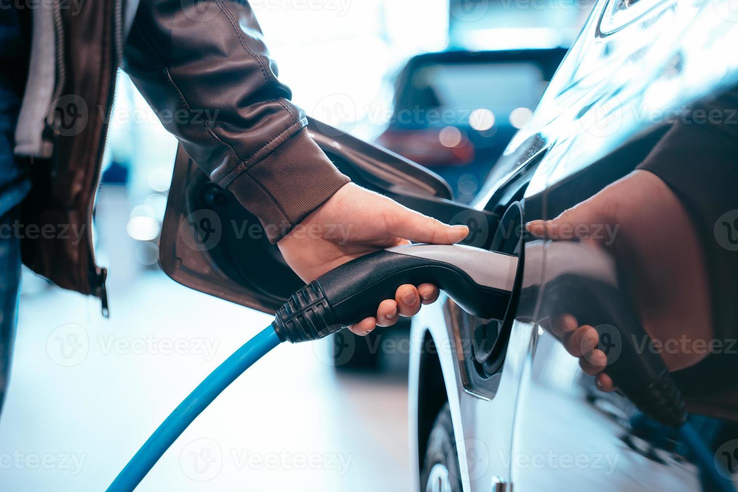 menselijke hand houdt elektrische auto opladen verbinding met elektrische auto foto