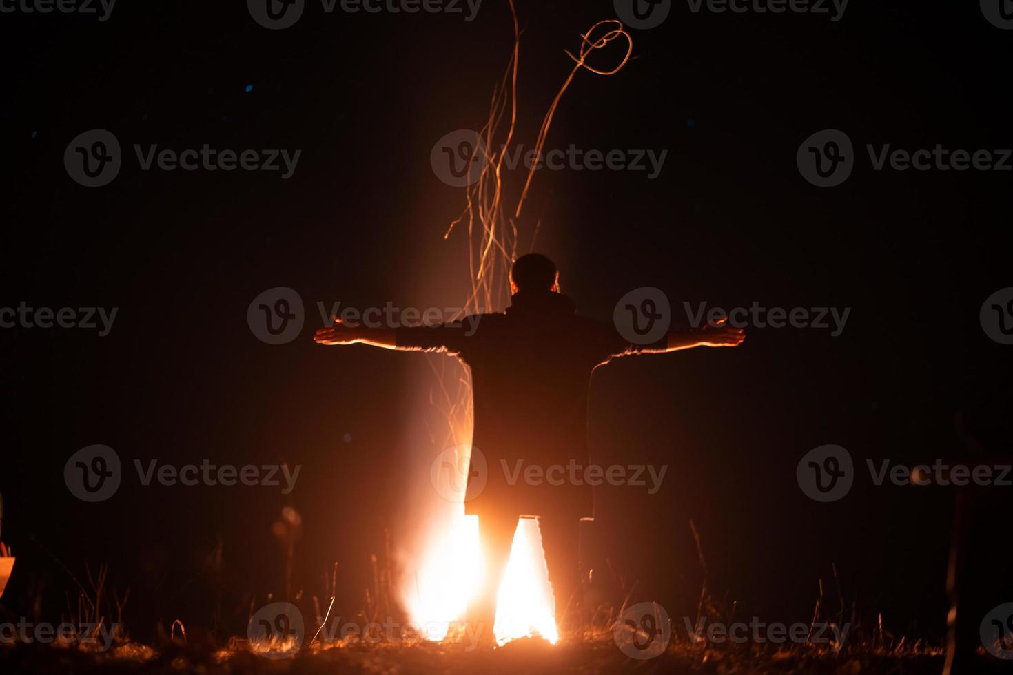 een Mens staat in voorkant van een brand met Open armen foto