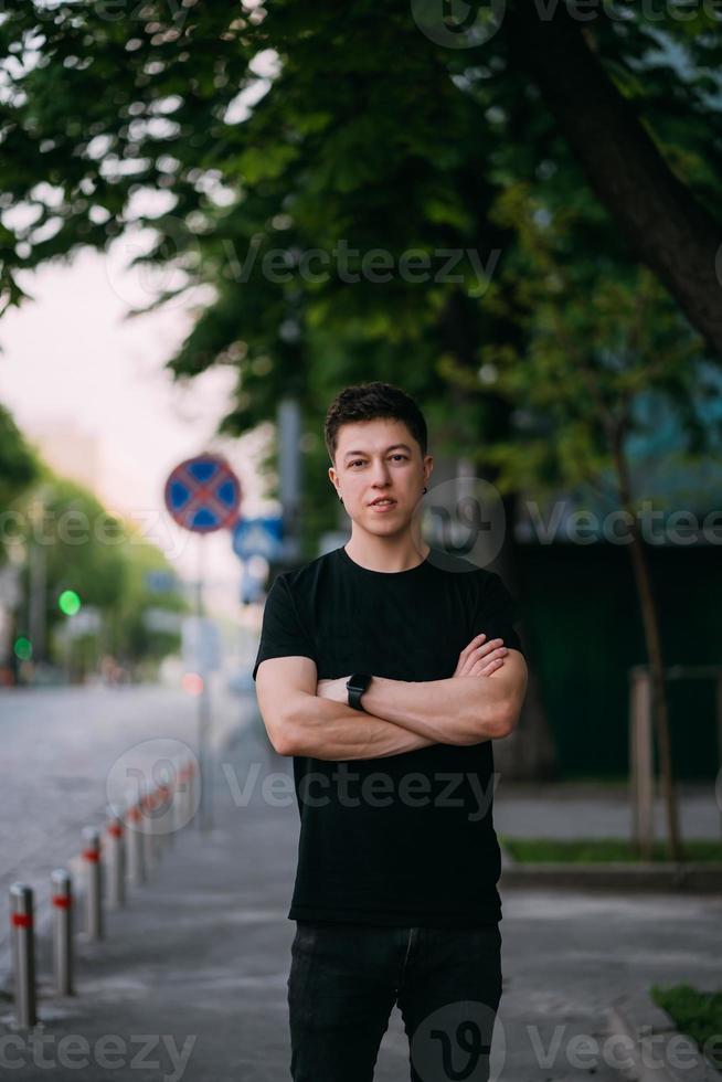 jong volwassen Mens in een zwart t-shirt en jeans wandelingen Aan een stad straat foto