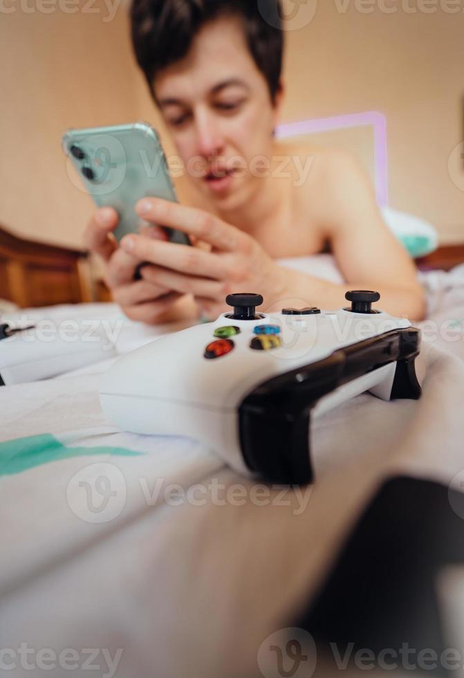 dichtbij omhoog schot van een vent aan het liegen in bed en gebruik makend van smartphone binnen. foto