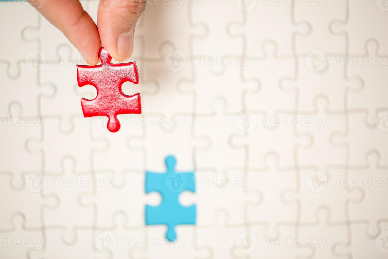 dichtbij omhoog hand- Holding en spelen decoupeerzaag spel incompleet. wit een deel van decoupeerzaag puzzel stukken Aan blauw achtergrond. concepten van probleem oplossen, bedrijf, teamwerk. foto