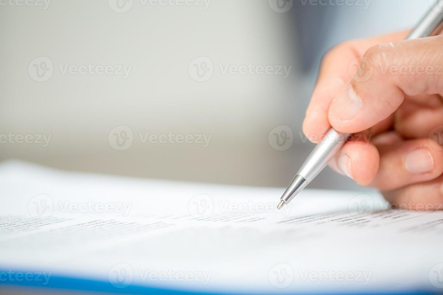 werkplaats detailopname persoon professioneel zakenvrouw zittend Bij bureau houden pen ondertekening of handtekening contract papier. werknemer vrouw schrijven overeenkomst document Aan papierwerk het formulier zakelijke Bij werk kantoor foto