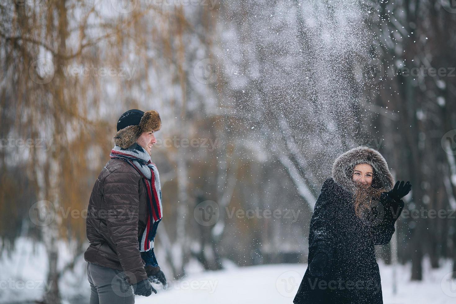 Mens en vrouw het werpen sneeuwballen foto