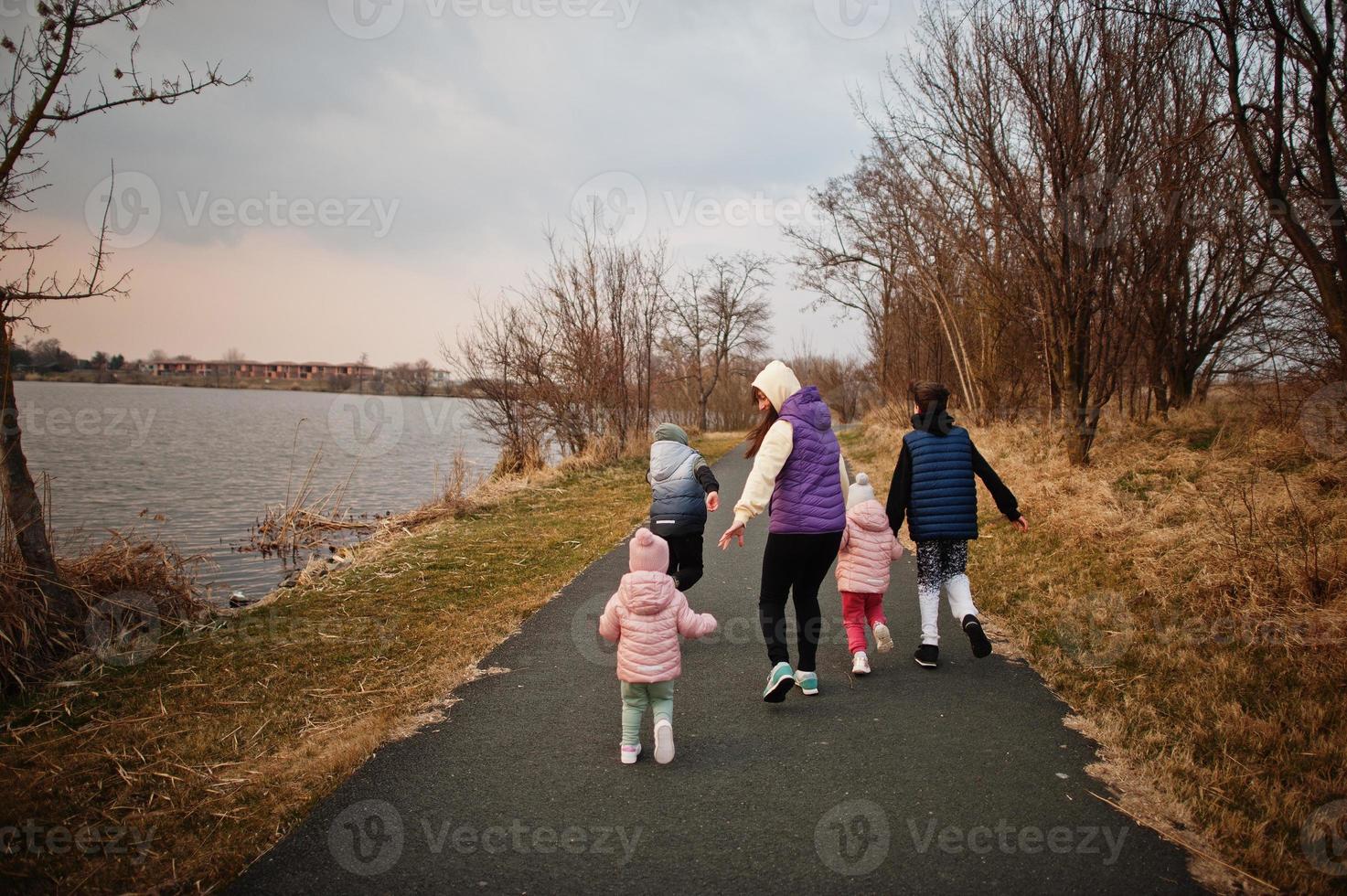 achterkant van moeder wandelen met kinderen op het pad bij het meer. foto