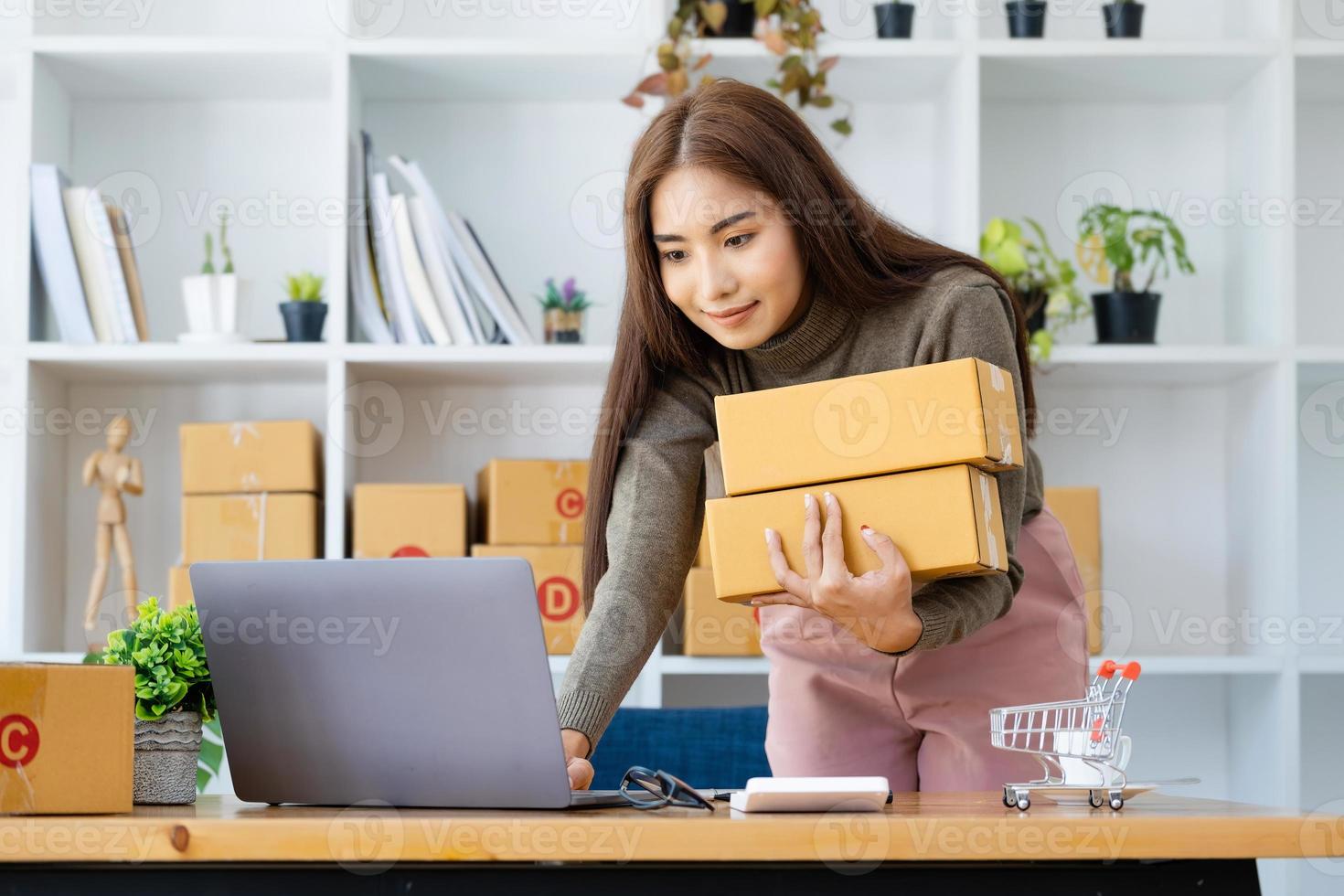 werk van huis. gelukkig Dames verkoop producten online begin een klein bedrijf eigenaar door gebruik makend van laptop computer naar berekenen prijzen en bereiden voor port. foto