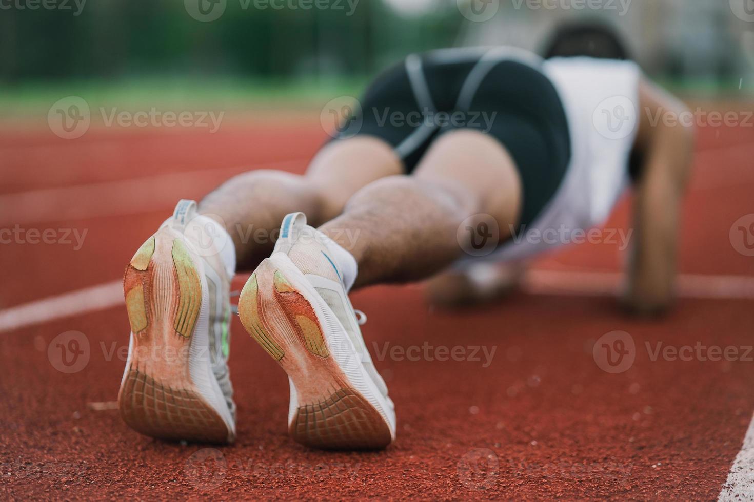 atleten sport Mens loper vervelend wit sportkleding naar planken uitrekken en warm omhoog voordat beoefenen Aan een rennen bijhouden Bij een stadion. loper sport concept. foto