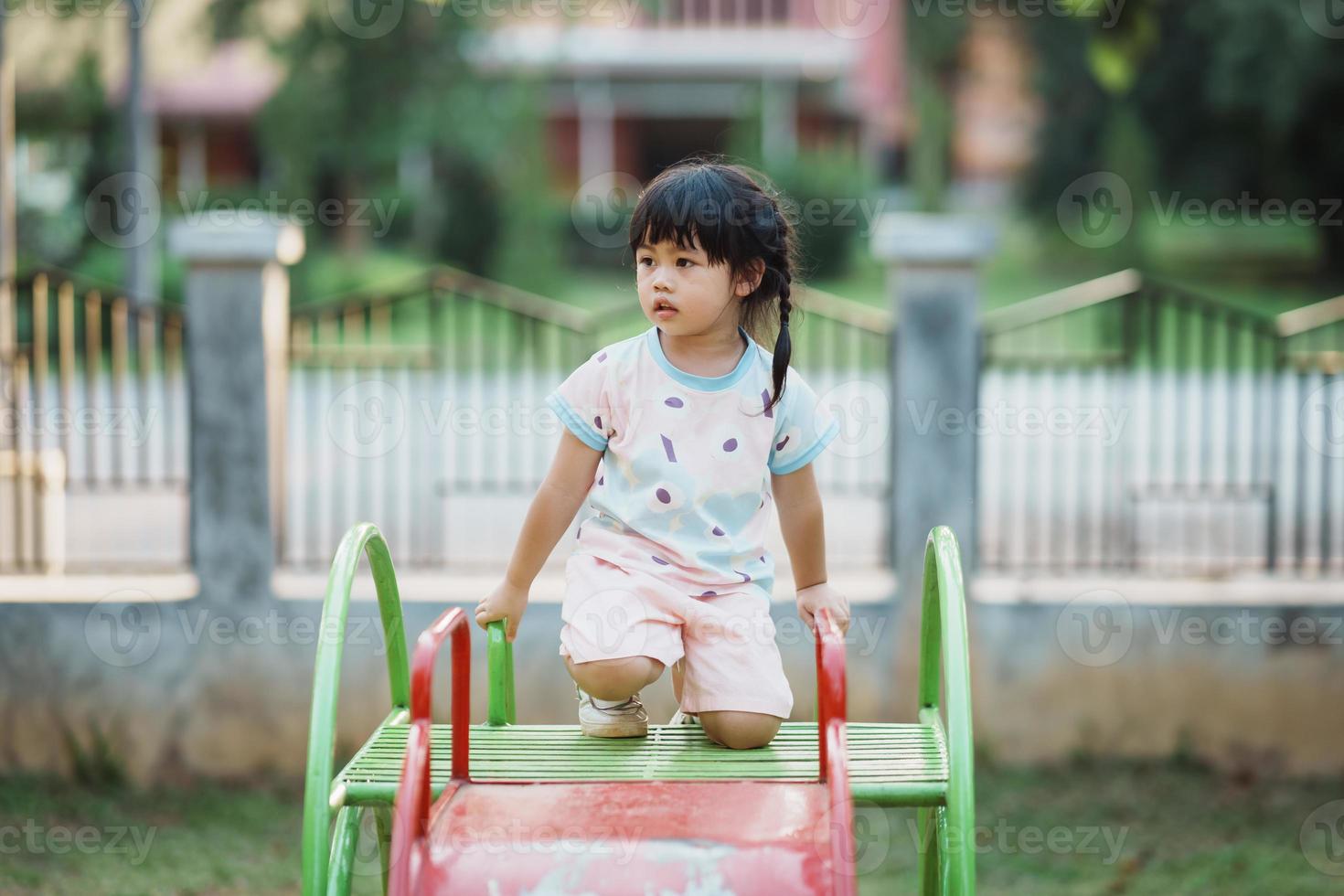 schattig Aziatisch meisje glimlach Speel Aan school- of kleuterschool werf of speelplaats. gezond zomer werkzaamheid voor kinderen. weinig Aziatisch meisje beklimming buitenshuis Bij speelplaats. kind spelen Aan buitenshuis speelplaats. foto