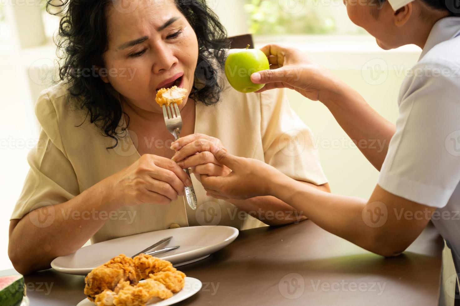 verpleegster suggereren volwassen vrouw geduldig naar eten appel in plaats daarvan van kip gebakken. foto