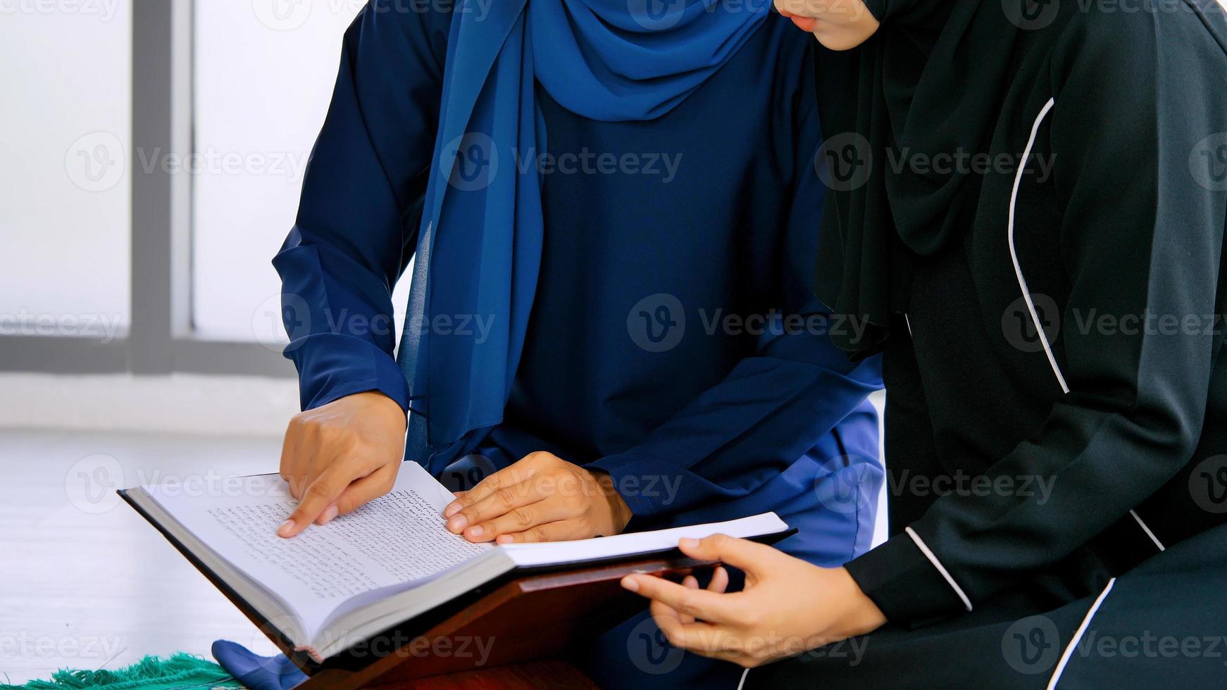 twee moslim Aziatisch Dames vervelend traditioneel hijab zijn reciteren gebeden in de koran. foto