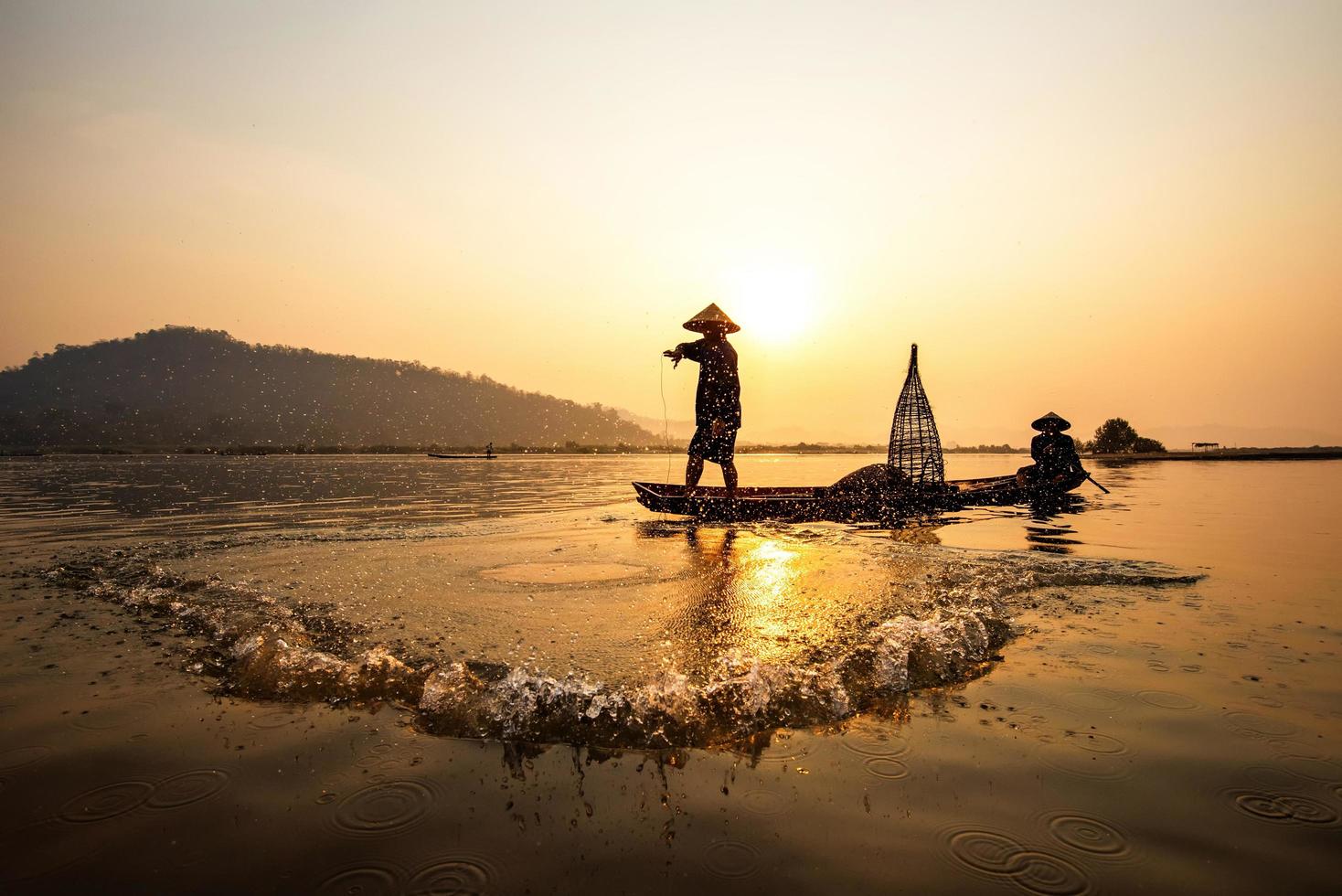 Azië visser netto gebruik makend van Aan houten boot gieten netto zonsondergang of zonsopkomst in de Mekong rivier- - silhouet visser foto