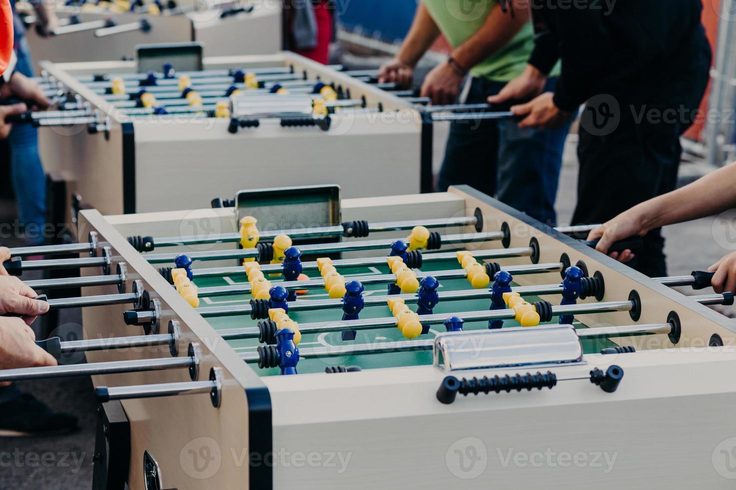 mensen, entertainment en recreatie concept. onherkenbare vrienden hebben samen plezier, spelen tafelvoetbal of kicker, rusten in de pub buiten foto