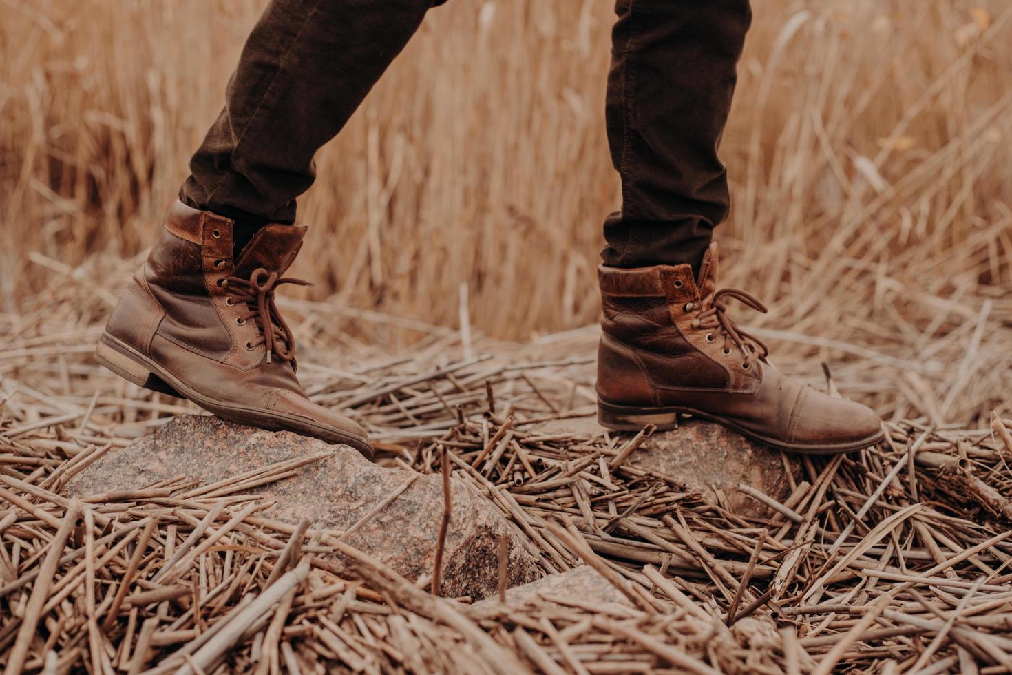bruine herenschoenen op het platteland. onherkenbaar mannelijk in broek en laarzen. leren oude schoenen. buiten lopen foto