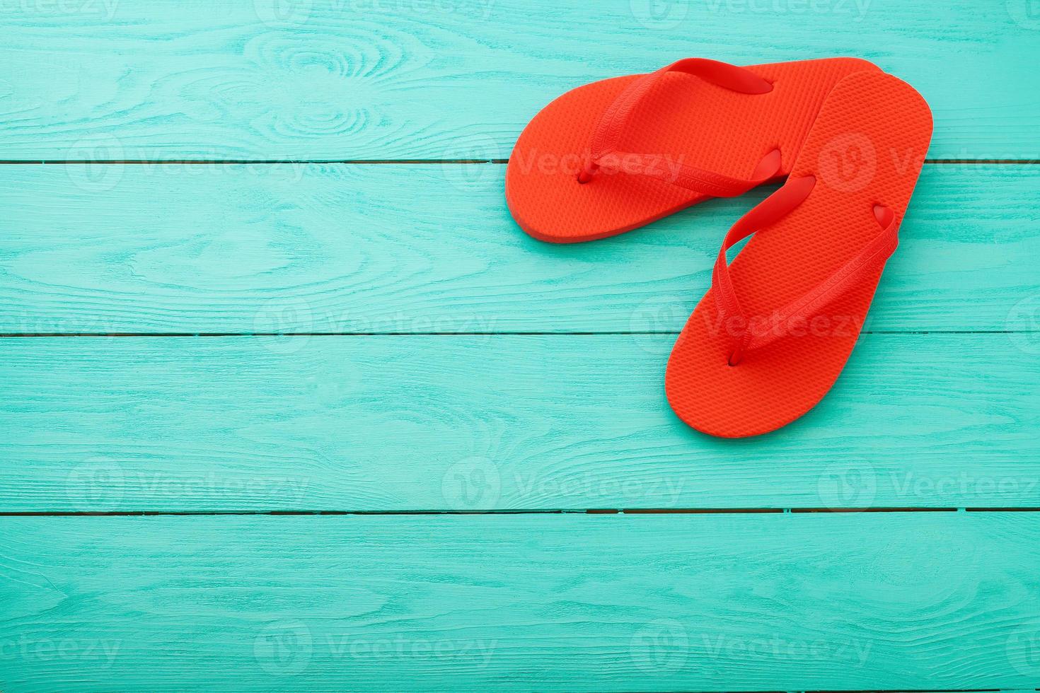 rood omdraaien flops Aan blauw houten achtergrond. zomer vakantie. slippers Aan de strand. top visie. bespotten omhoog. kopiëren ruimte foto