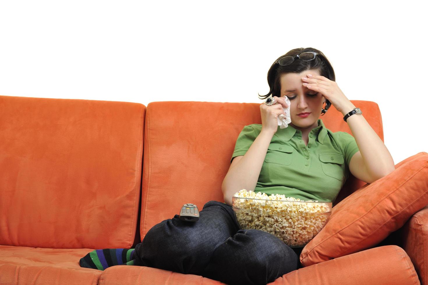 jong vrouw eten popcorn en aan het kijken TV foto