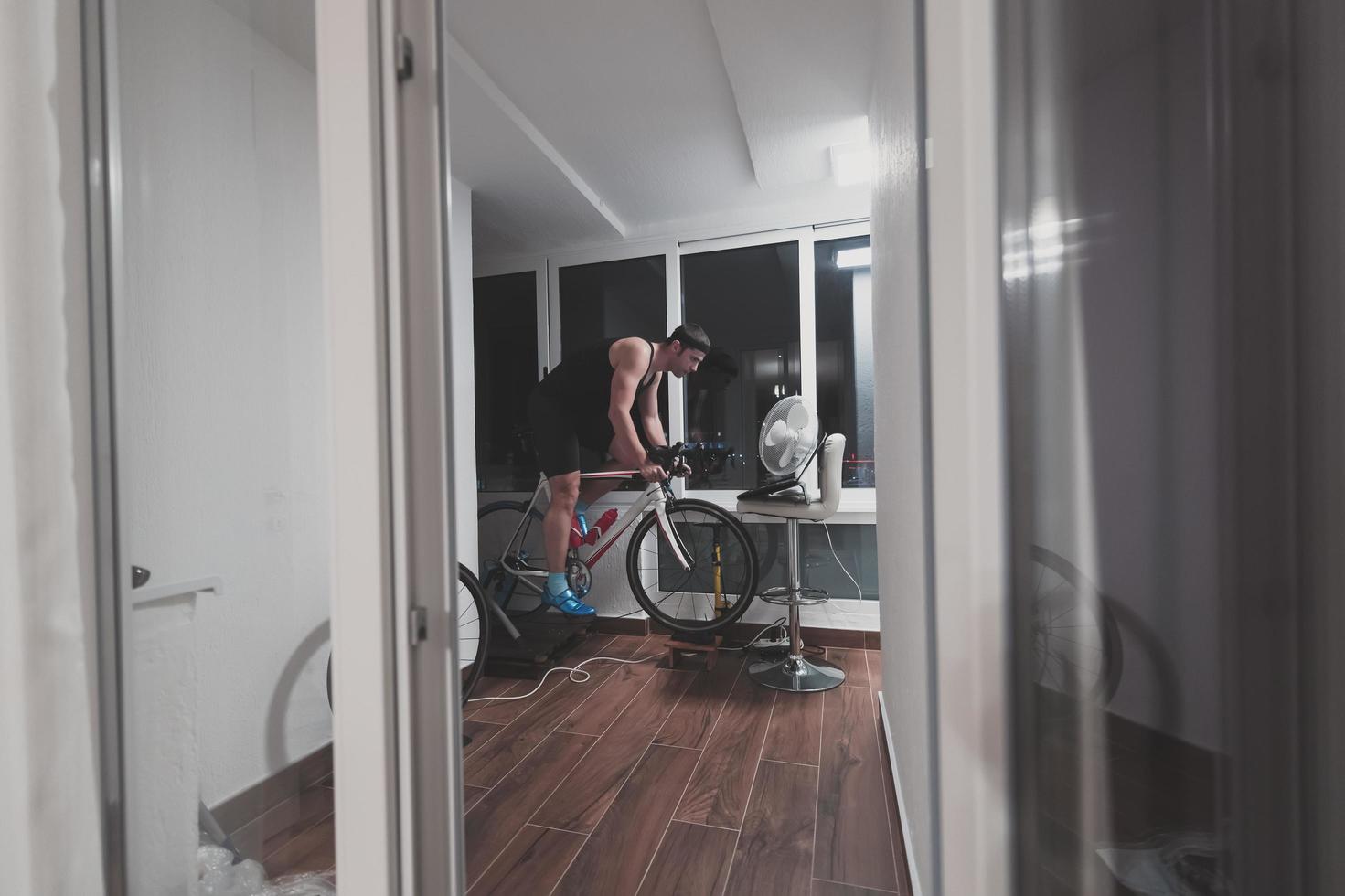 Mens wielersport Aan de machine trainer hij is oefenen in de huis Bij nacht spelen online fiets racing spel foto