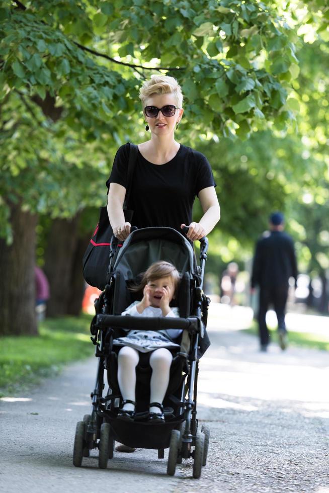 moeder geduwd haar baby dochter in een wandelwagen foto