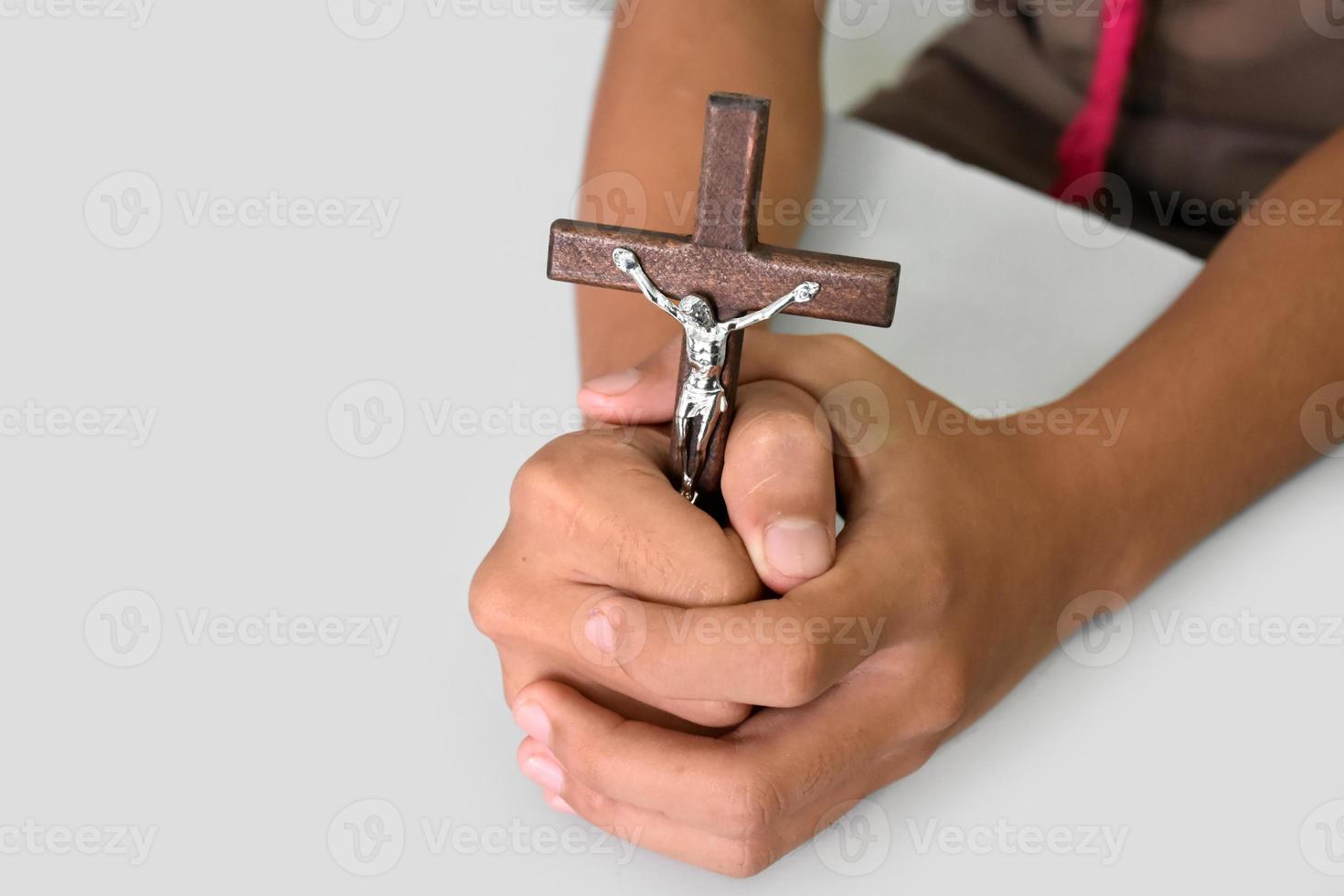 houten kruis met een standbeeld van Jezus gekruisigd door zijn arm Holding in handen van gebed Aan wit tafel in de kerk, zacht en selectief focus. foto