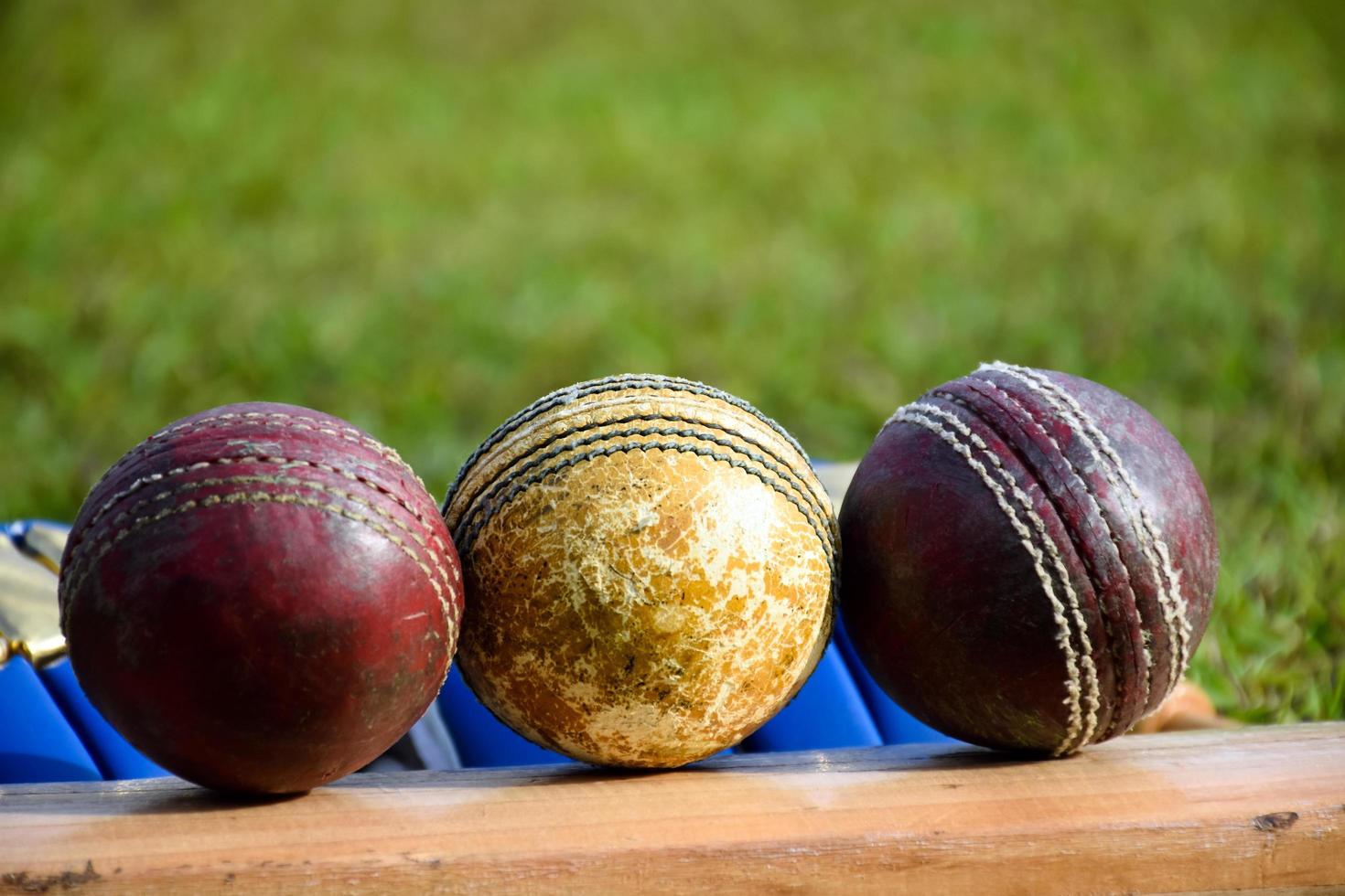 krekel sport uitrustingen knuppel bal handschoenen Aan groen gazon wazig groen gras krekel veld, concept voor gebruik makend van krekel sport uitrusting in opleiding. foto