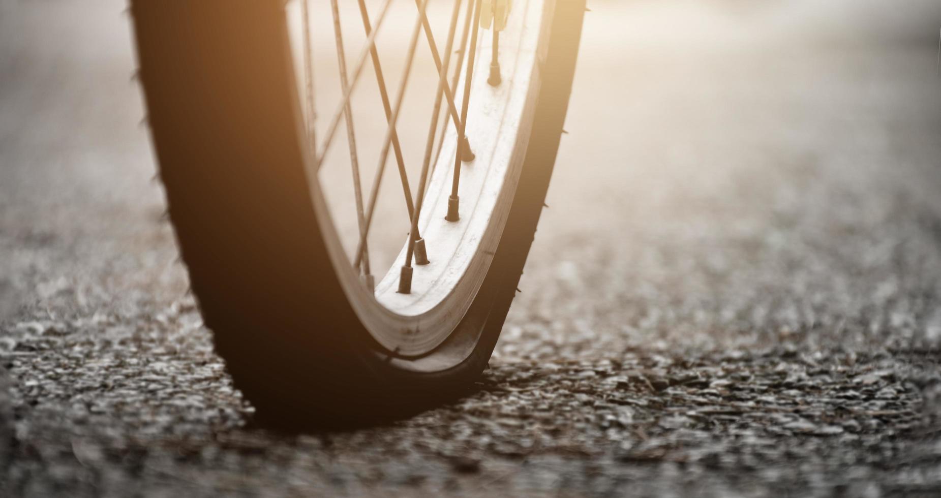 detailopname achterzijde vlak wiel van wijnoogst fiets Aan bestrating in de avond van de dag, zonsondergang licht bewerkt, zacht en selectief focus foto