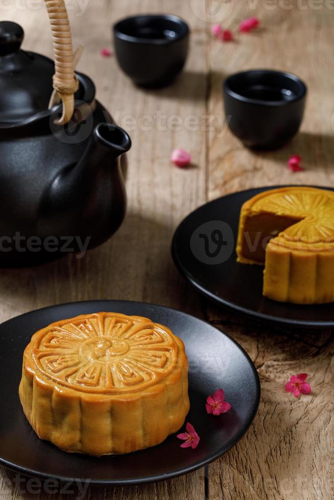heerlijk voedsel maan taart met kop van heet thee Aan de de houten tafel achtergrond met copyspace voor uw tekst, Chinese traditioneel festival concept foto