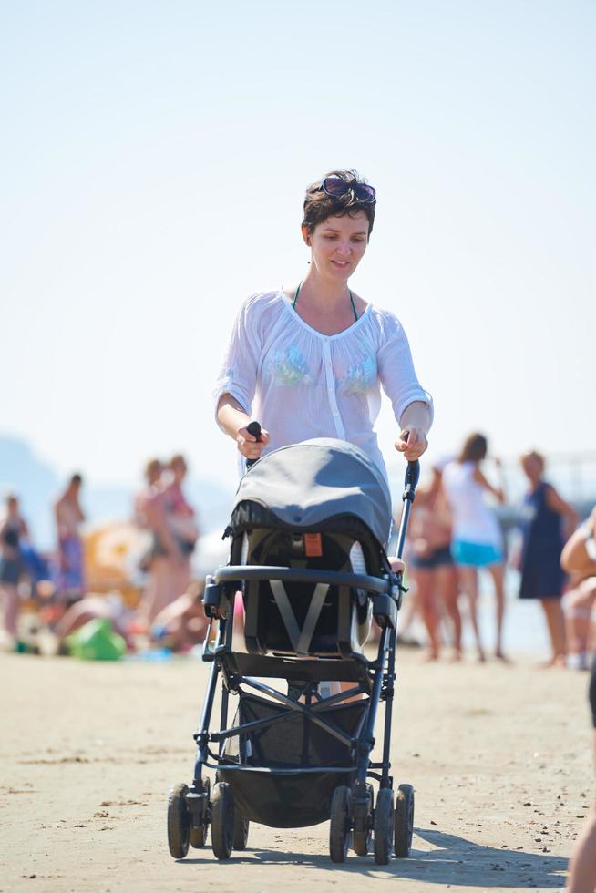 moeder wandelen Aan strand en Duwen baby vervoer foto